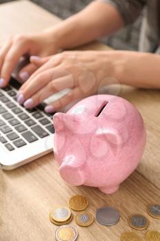 Cute piggy bank with coins on wooden table in office�