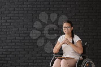 Female teacher in wheelchair near brick wall�