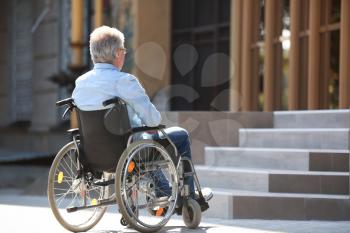Senior man in wheelchair near stairs outdoors�