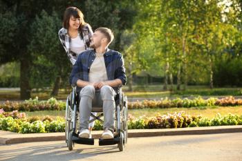 Young man in wheelchair and his wife outdoors�