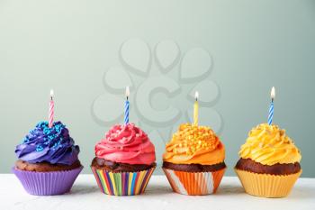 Delicious birthday cupcakes with candles on white table�