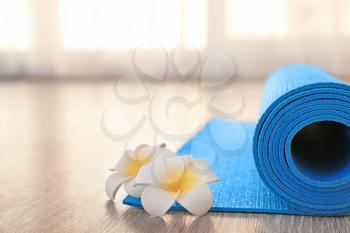 Rolled yoga mat and flowers on floor�