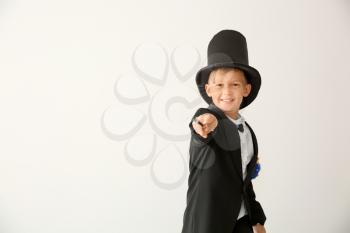 Cute little magician showing tricks on white background�