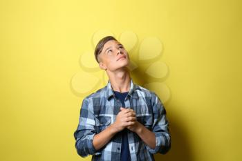 Thoughtful teenage boy on color background�
