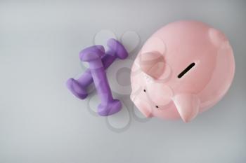Piggy bank with dumbbells on light background. Weight loss concept�