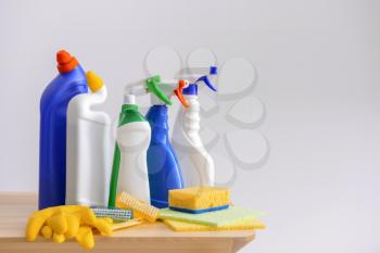 Cleaning supplies on wooden table against light background�