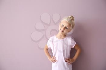 Cute little girl in t-shirt on color background�