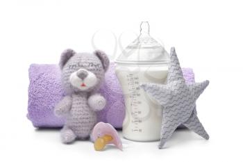 Feeding bottle of baby formula with toys and towel on white background�