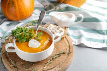 Casserole with tasty pumpkin cream soup on wooden board�