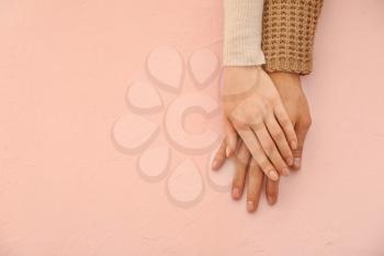 Hands of loving young couple on color background�