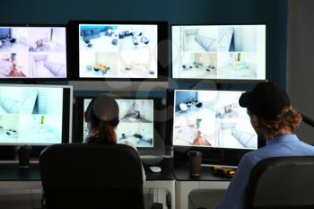 Security guards monitoring modern CCTV cameras in surveillance room�
