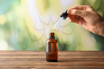 Female hand and bottle with eucalyptus essential oil on blurred background�
