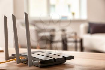 Modern wi-fi router on wooden table in room�
