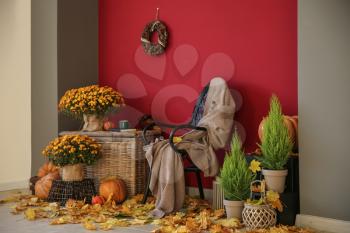 Beautiful autumn composition with chair and decorations near color wall�