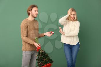 Young woman rejecting marriage proposal on color background�