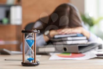 Hourglass on table of stressed businesswoman missing deadlines�