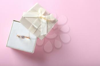 Box with beautiful engagement ring on color background�