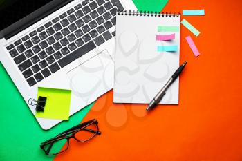 Laptop and school stationery on color background, top view�
