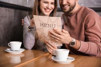 Young couple looking through menu in restaurant�