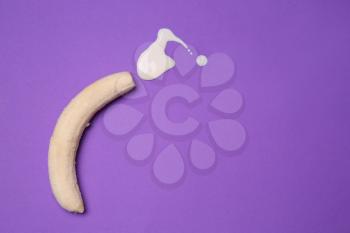 Fresh banana and white liquid on color background. Erotic concept�