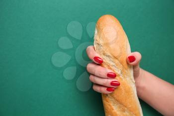 Woman holding fresh baguette on color background. Erotic concept�