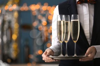 Waitress holding tray with glasses of champagne at party�