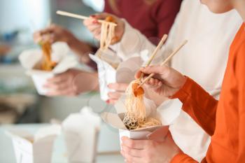 People eating chinese noodles from takeaway boxes, closeup�