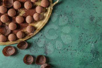 Metal tray with tasty chocolate truffles on color table�