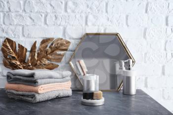 Soap with stack of clean towels on grey table in bathroom�