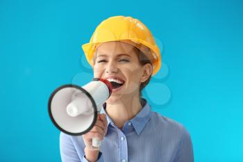 Female engineer using megaphone on color background�