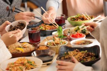 Friends eating tasty Chinese food at table�