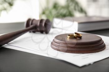 Rings with decree of divorce and judge gavel on table�