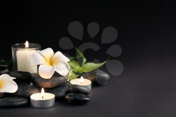 Beautiful spa composition with stones, candles and flowers on dark background�