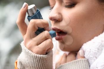 Young woman with inhaler having asthma attack outdoors, closeup�