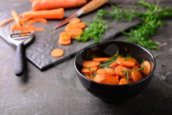 Bowl with tasty fermented carrot on grey table�