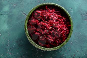Bowl with tasty fermented beetroot on green table�