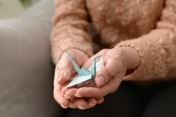 Young woman holding origami bird, closeup�