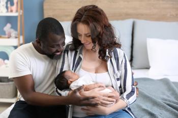 Happy interracial couple with their little daughter at home�