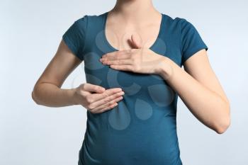 Pregnant woman touching her breast on light background�