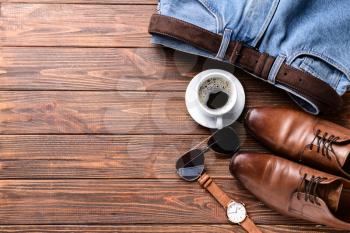 Stylish male clothes with accessories and cup of coffee on wooden table�