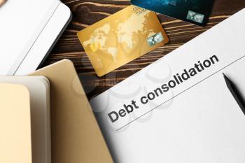Paper with text DEBT CONSOLIDATION, notebooks and credit cards on table�