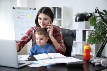 Young mother with her son working in office�