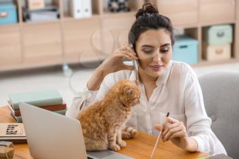 Young woman with cute funny cat working at home�