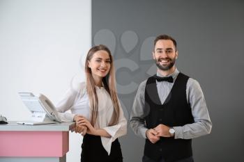 Male and female receptionists near desk in hotel�