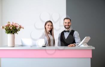 Male and female receptionists at desk in hotel�