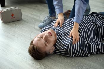 Woman providing first aid to her unconscious husband at home�