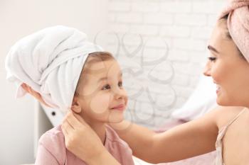Cute little daughter with her mother after shower at home�