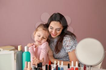 Cute daughter with mother making manicure at home�