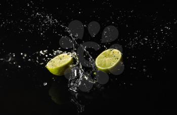 Ripe cut lime with water splash on dark background�