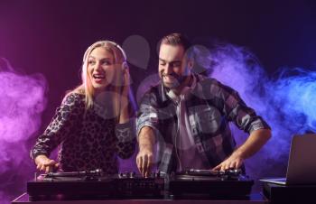 Male and female DJs playing music in club�
